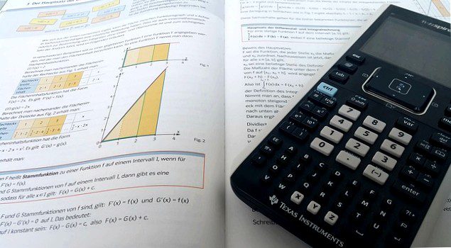 Calculator on an open math book: If you want to calculate the interest savings for a debt restructuring, you need mathematical understanding!